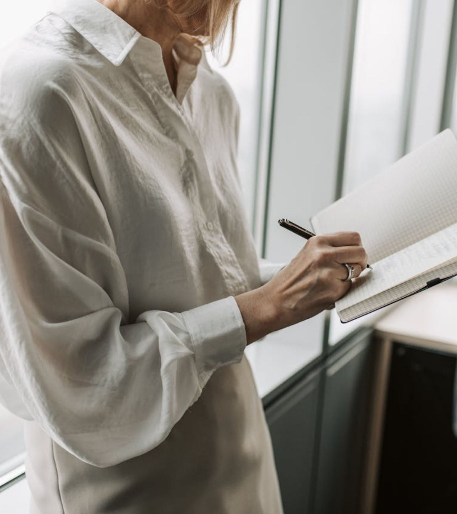 Kvinna på en arbetsplats med penna och skrivblock i handen